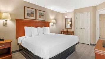 Una habitación de hotel con una cama grande, mesitas de noche, un escritorio y un armario.