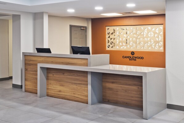 Un mostrador de recepción de diseño moderno, con detalles de madera y el logotipo de Candlewood Suites.