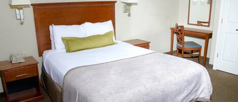 A hotel room with a bed, a desk, a chair, a telephone, and two wall-mounted lamps.