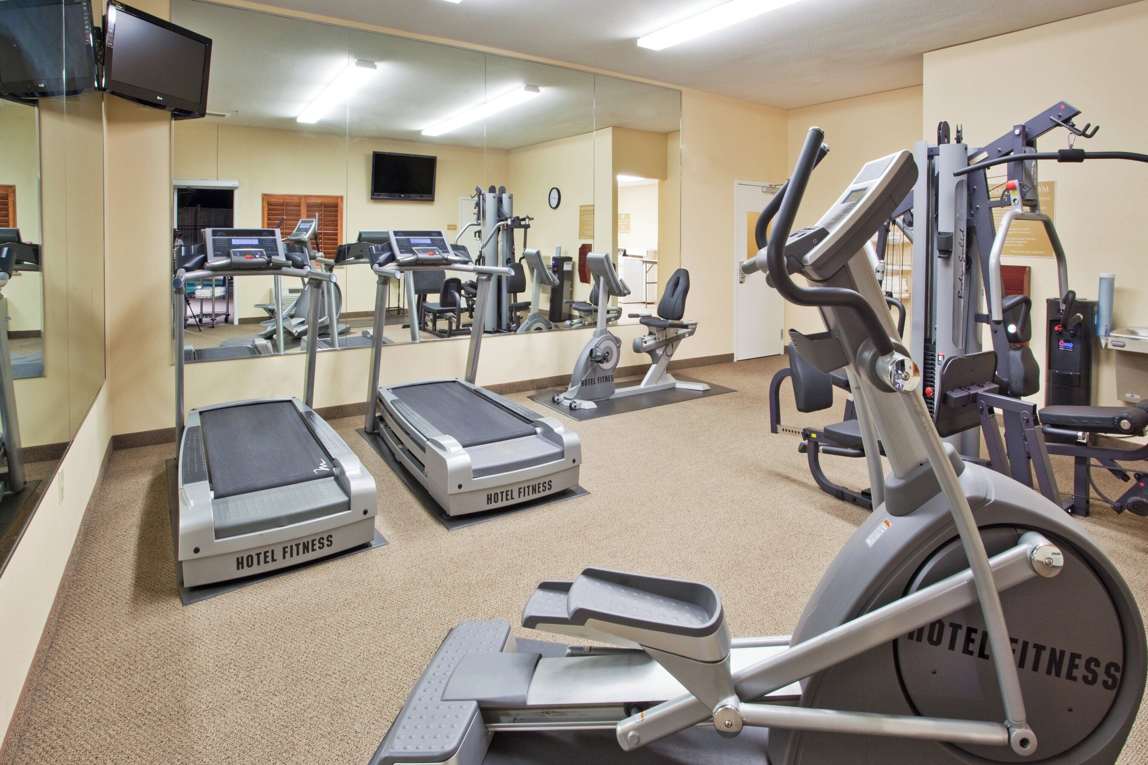 A hotel fitness center with treadmills, elliptical machines, and weight equipment.