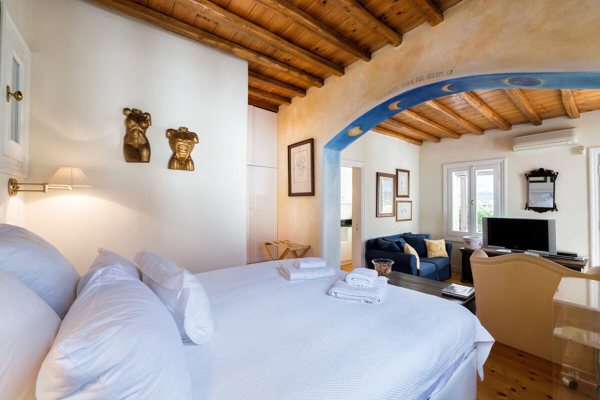 A hotel room with a large bed, a desk, a television, and a sofa.