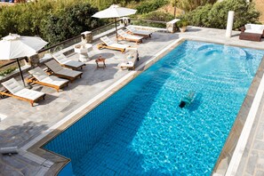 A swimming pool with lounge chairs and umbrellas. - Villa Galaxy (Mykonos)