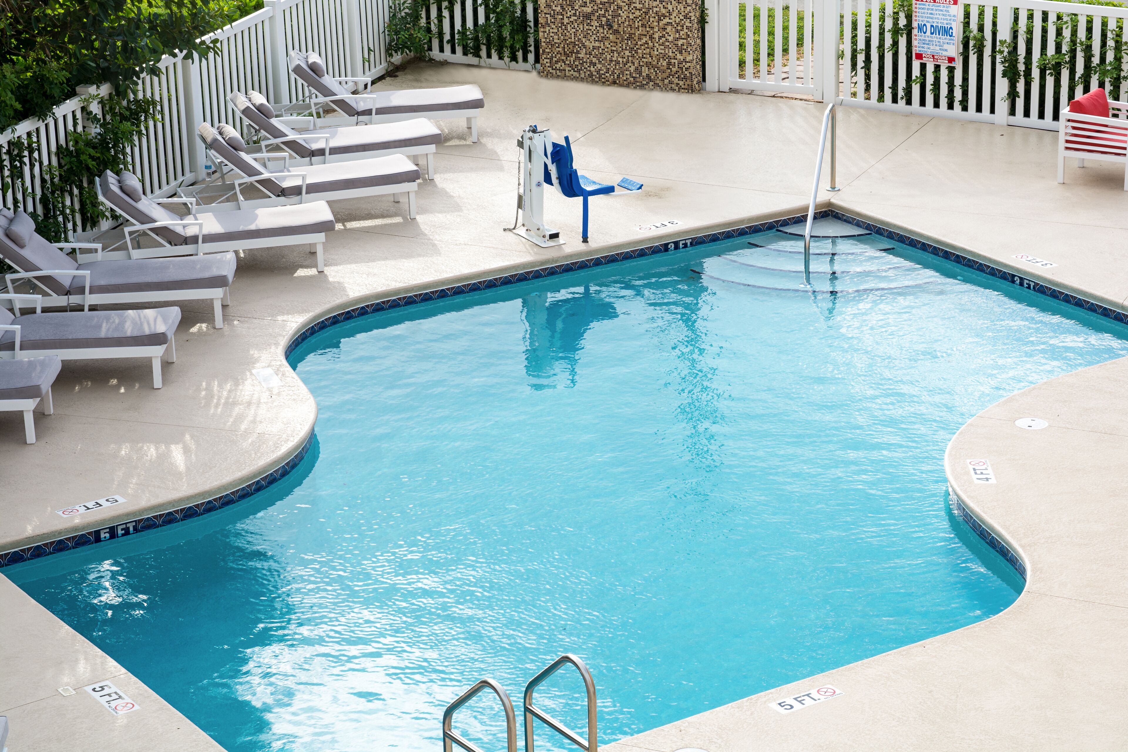 A swimming pool with lounge chairs, a diving board, and a 'No Diving' sign.