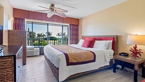 A hotel room with a large bed, a ceiling fan, a view of palm trees, and a balcony. - The Royal Inn Beach Hotel Hutchinson Island (Fort Pierce)