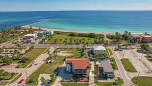 An aerial view of a coastal area with a beach, a road, and several buildings including a large white building with a red roof. - The Royal Inn Beach Hotel Hutchinson Island (Fort Pierce)