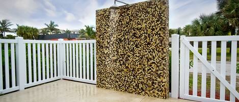 A gated entrance with a tiled wall and a white fence.
