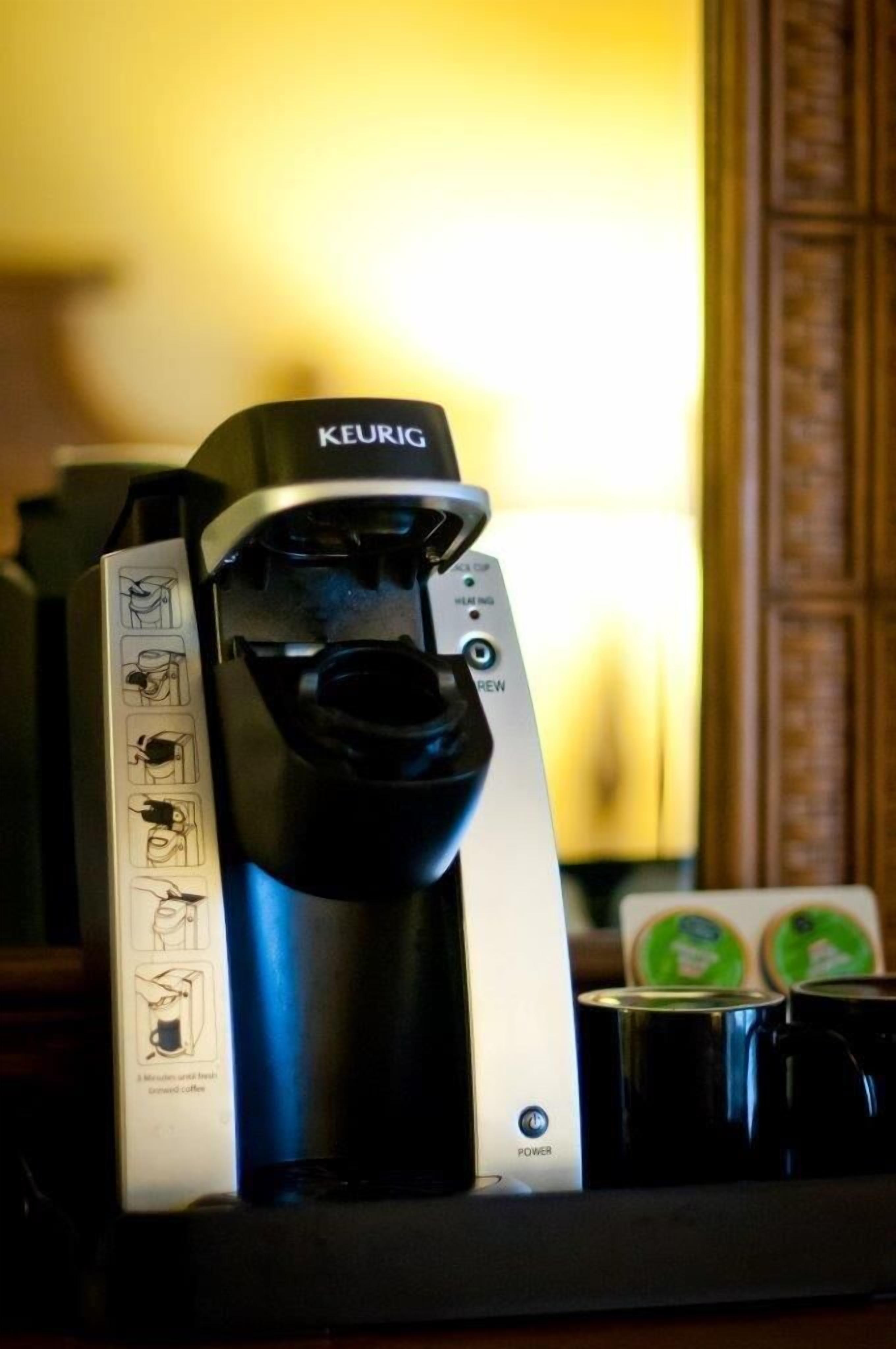 Máquina de café Keurig com manual e sachês de café sobre um balcão.