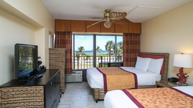 A hotel room with two beds, a television, a ceiling fan, and a view of the beach. - The Royal Inn Beach Hotel Hutchinson Island (Fort Pierce)