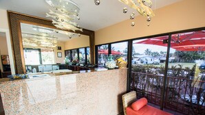 A reception area with a marble counter, a large mirror, and a wicker sofa. - The Royal Inn Beach Hotel Hutchinson Island (Fort Pierce)
