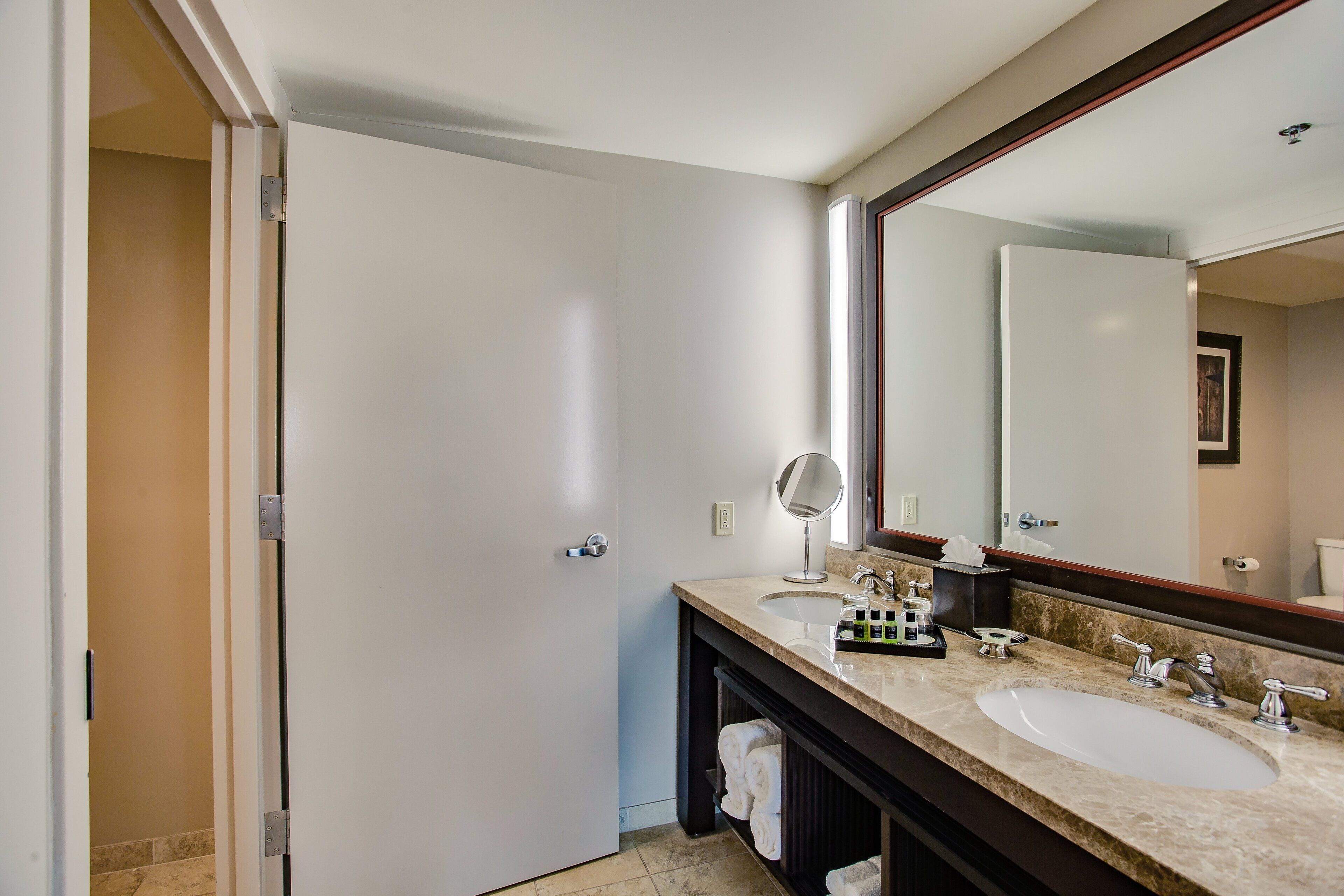 Un baño moderno con lavamanos doble, un espejo grande y un perchero para toallas.