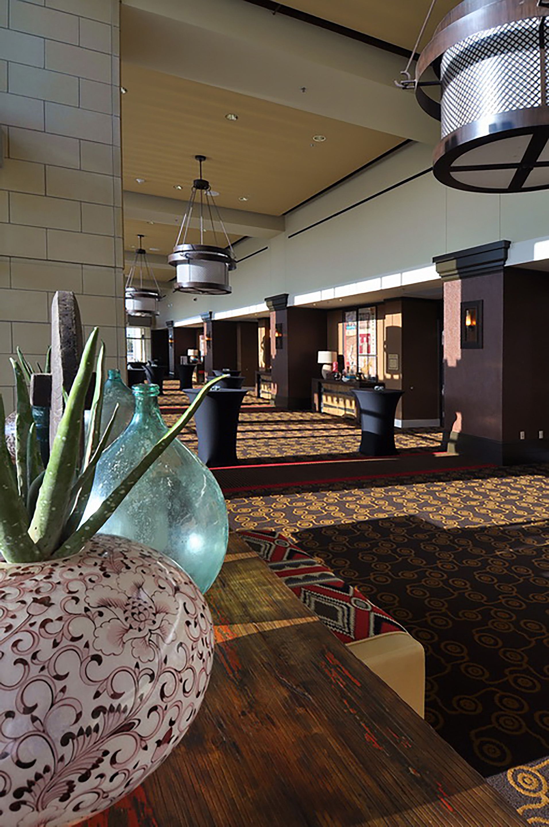 Un hall d’entrée avec un tapis à motifs, un comptoir de réception et un grand vase décoratif.