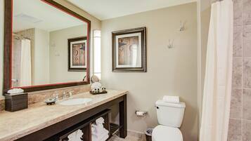 A bathroom with a double sink, a toilet, a large mirror, and a shower curtain.