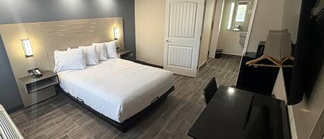 A hotel room with a bed, bedside tables, a desk, and a wardrobe.