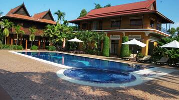 Una piscina al aire libre, sombrillas, sillones reclinables de piscina