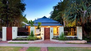 A modern house with a blue roof, surrounded by lush greenery and a brick pathway leading to the entrance. - Bay Haven Lodge (Byron Bay)