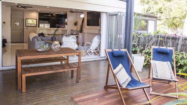 An open-plan living area with a wooden table and two lounge chairs. - Bay Haven Lodge (Byron Bay)