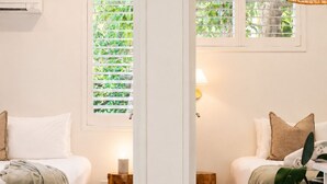 A room with a bed, bedside table, and a window with blinds. - Bay Haven Lodge (Byron Bay)