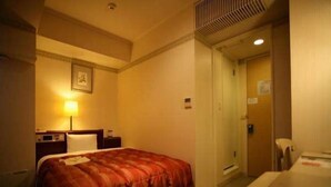 Une chambre d’hôtel avec un lit, une table de chevet, une lampe et une porte donnant sur une autre pièce.