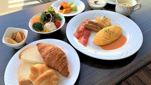 Une table garnie de divers aliments pour le petit-déjeuner, notamment des croissants, du pain, des fruits et de la soupe.