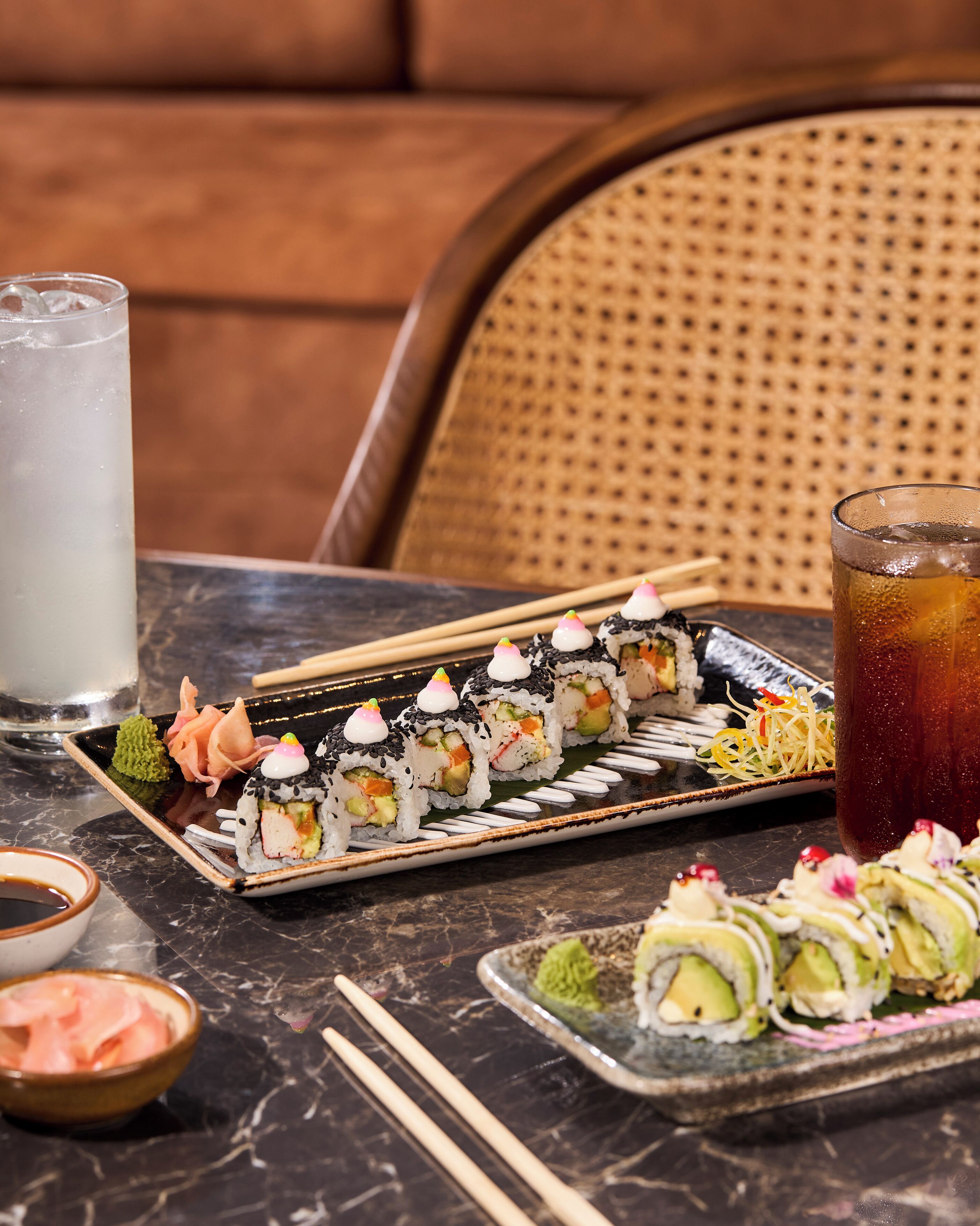 Ein Tisch mit Sushi, einem Glas Eistee und einer Sojasaucenschale.