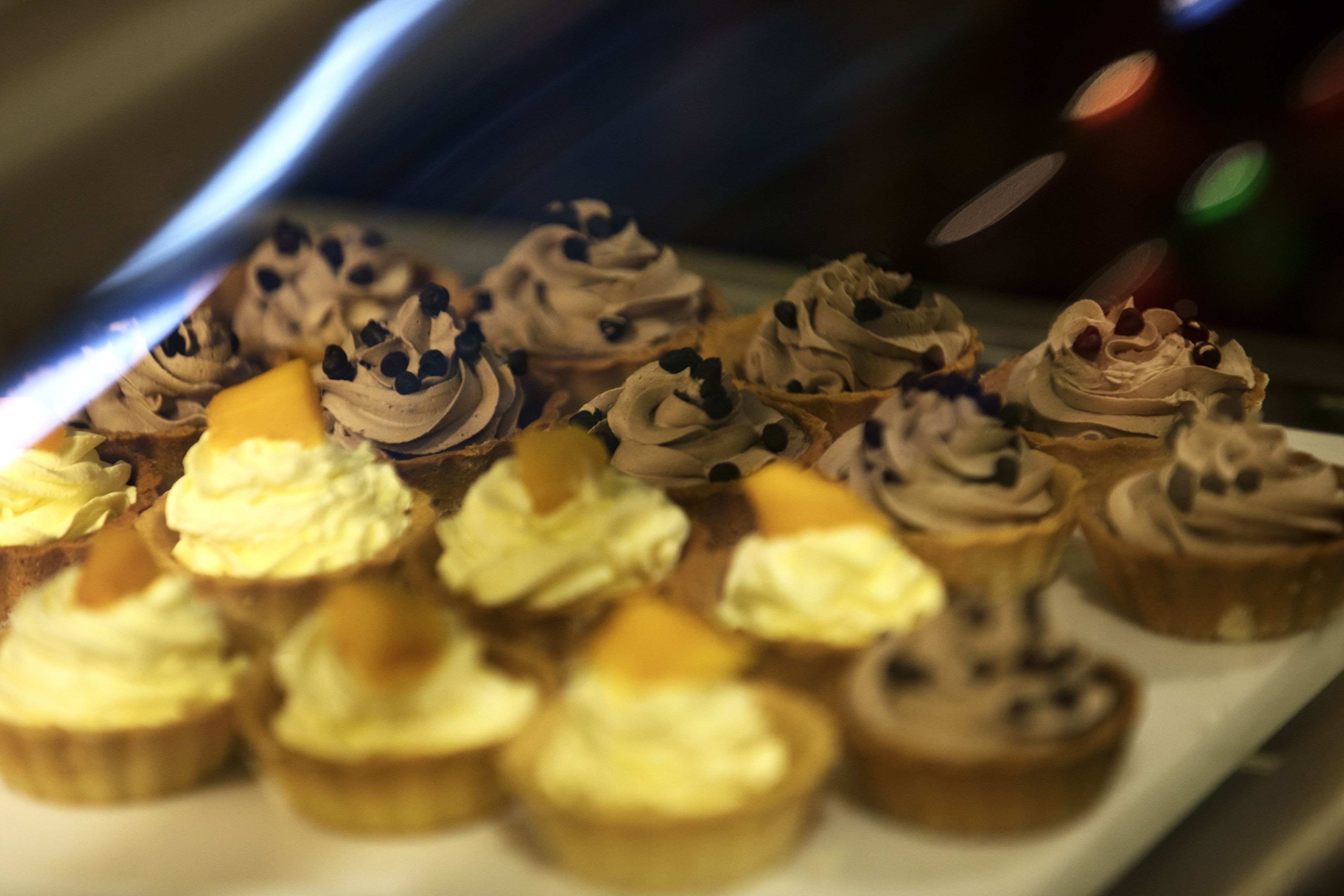 A variety of cupcakes with different toppings, arranged on a tray.