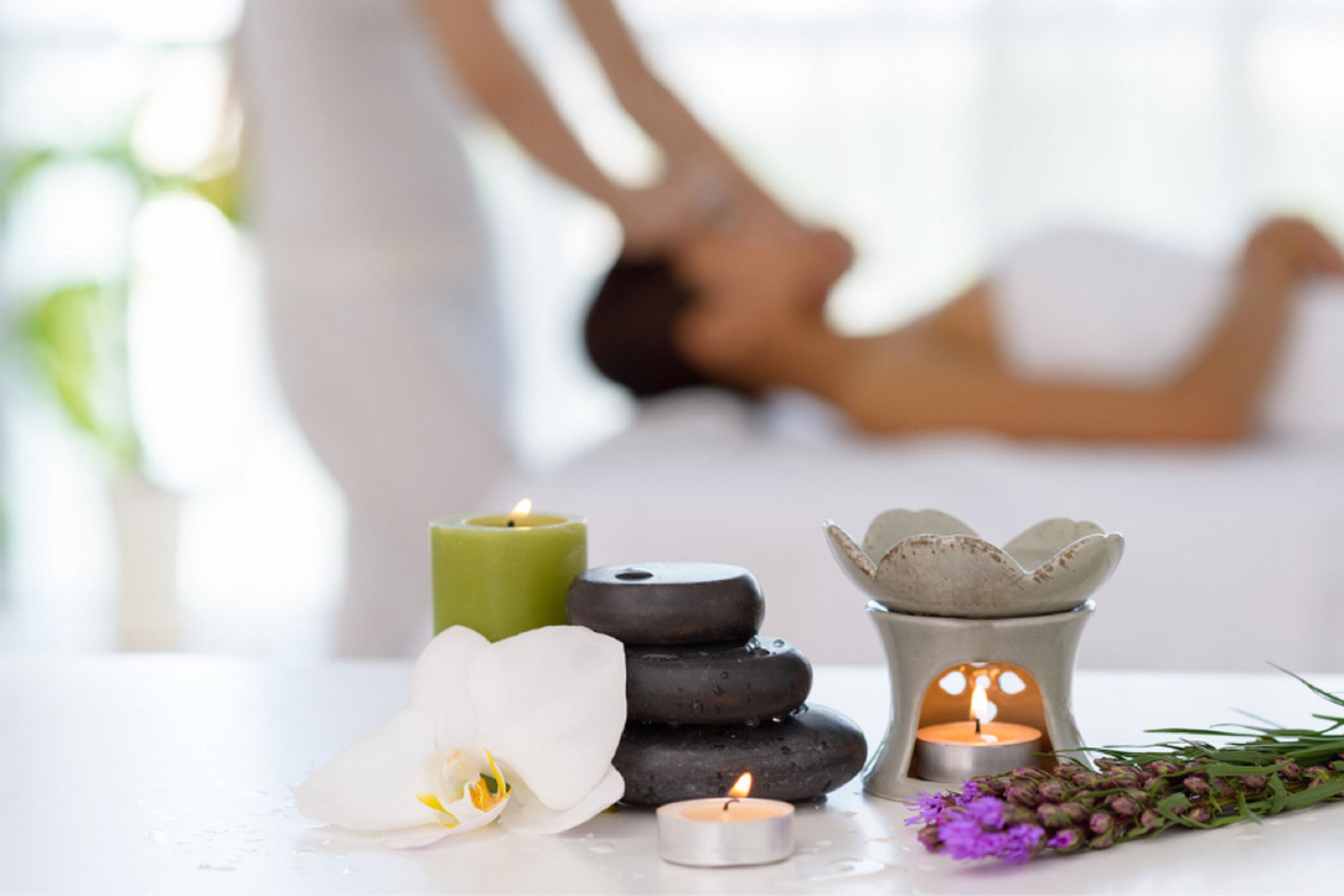 A spa setting with a massage table, candles, and flowers.