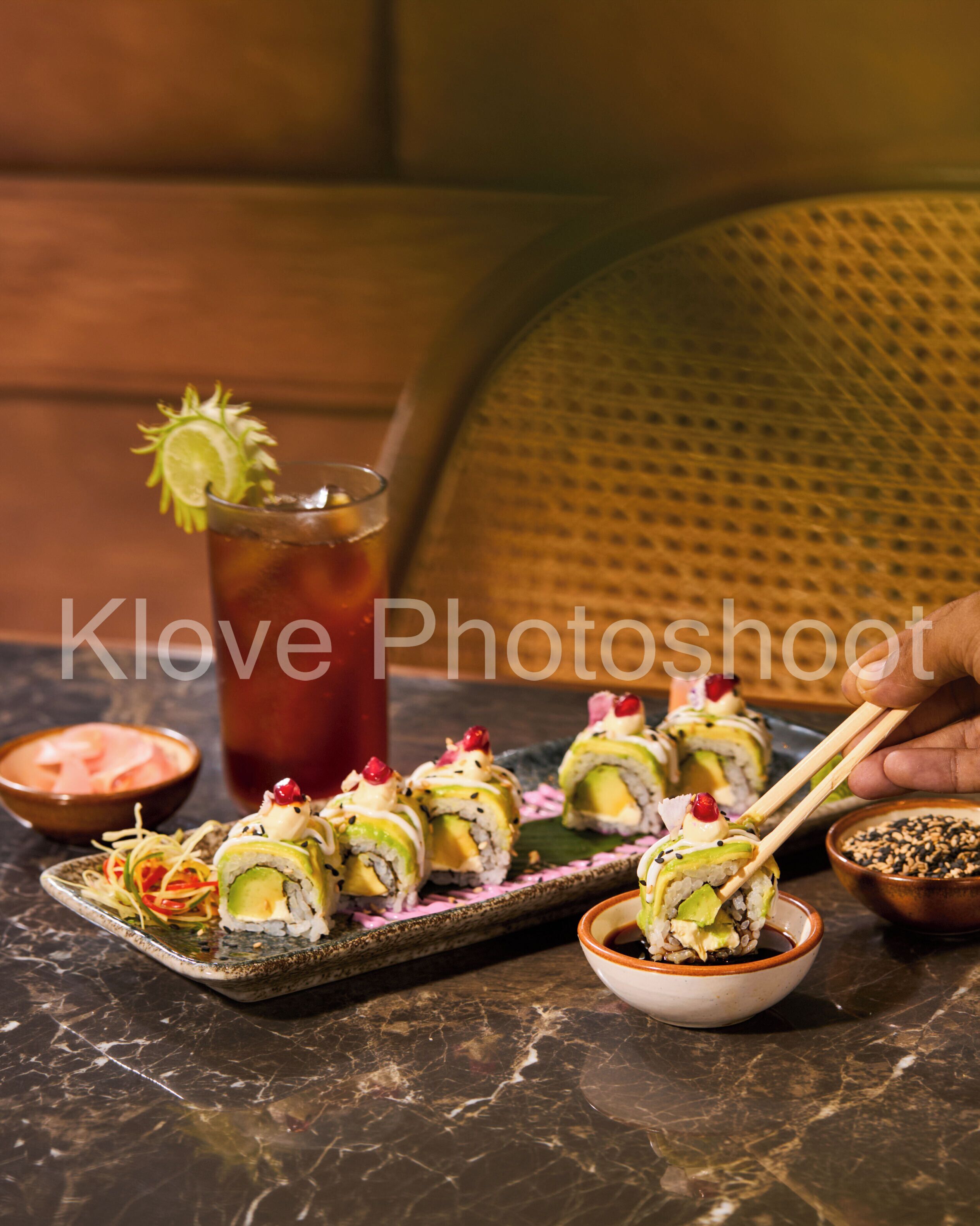 Sushirollen op een bord, een drankje met een limoen en een schaaltje saus.