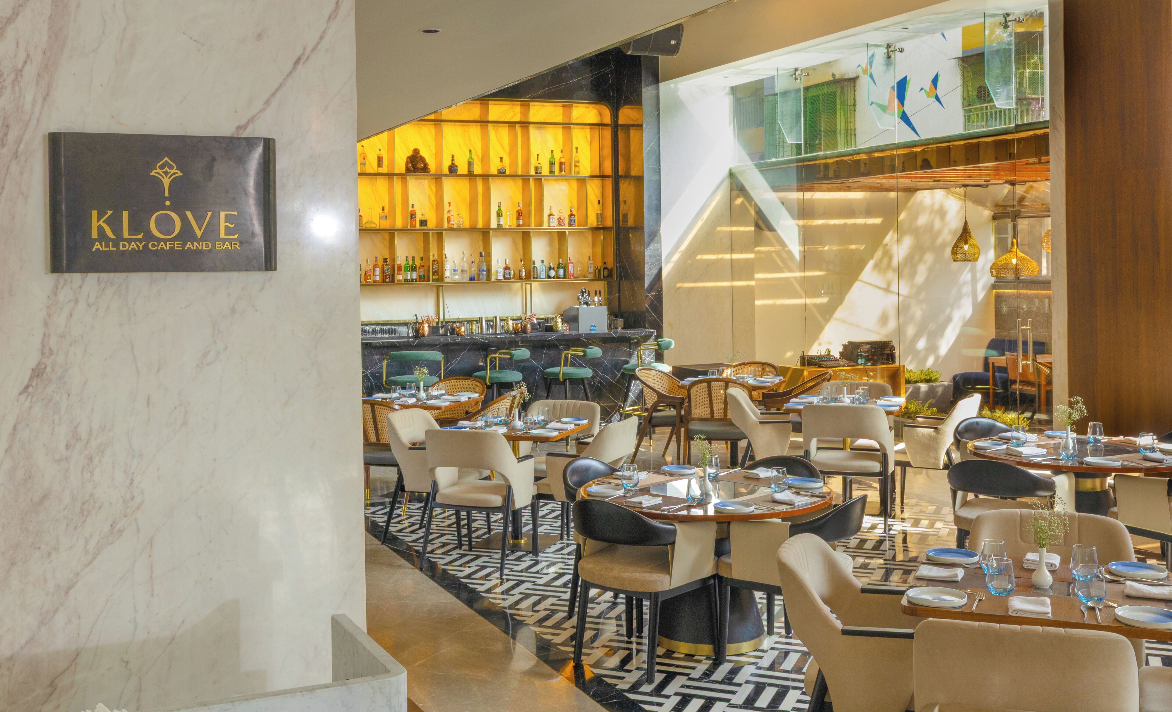 Un restaurante con paredes de mármol, una zona de bar con estantes llenos de botellas y un suelo con diseño.