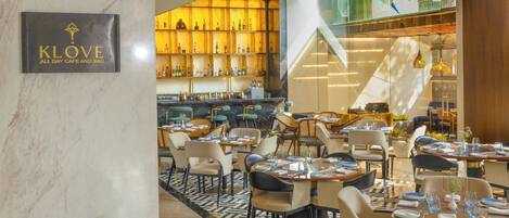 Un restaurante con paredes de mármol, una zona de bar con estantes llenos de botellas y un suelo con diseño.