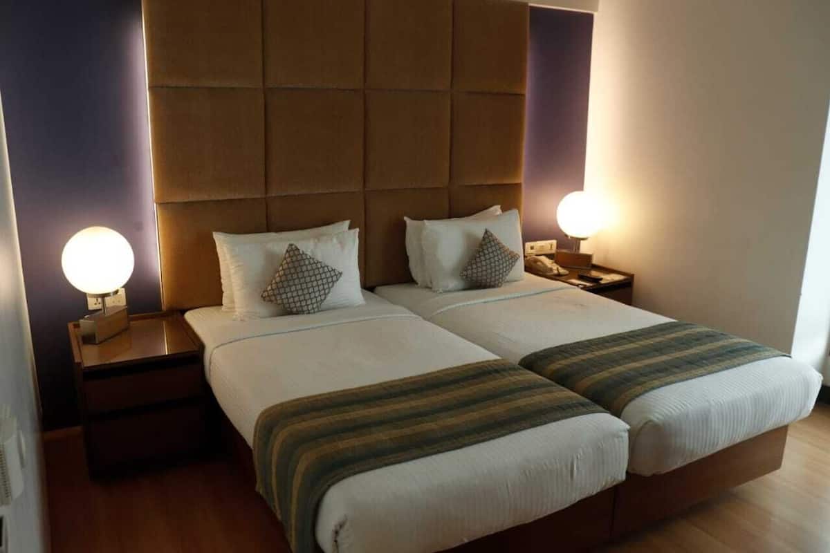 A double room with two beds, each with a headboard, bedside tables, and lamps.