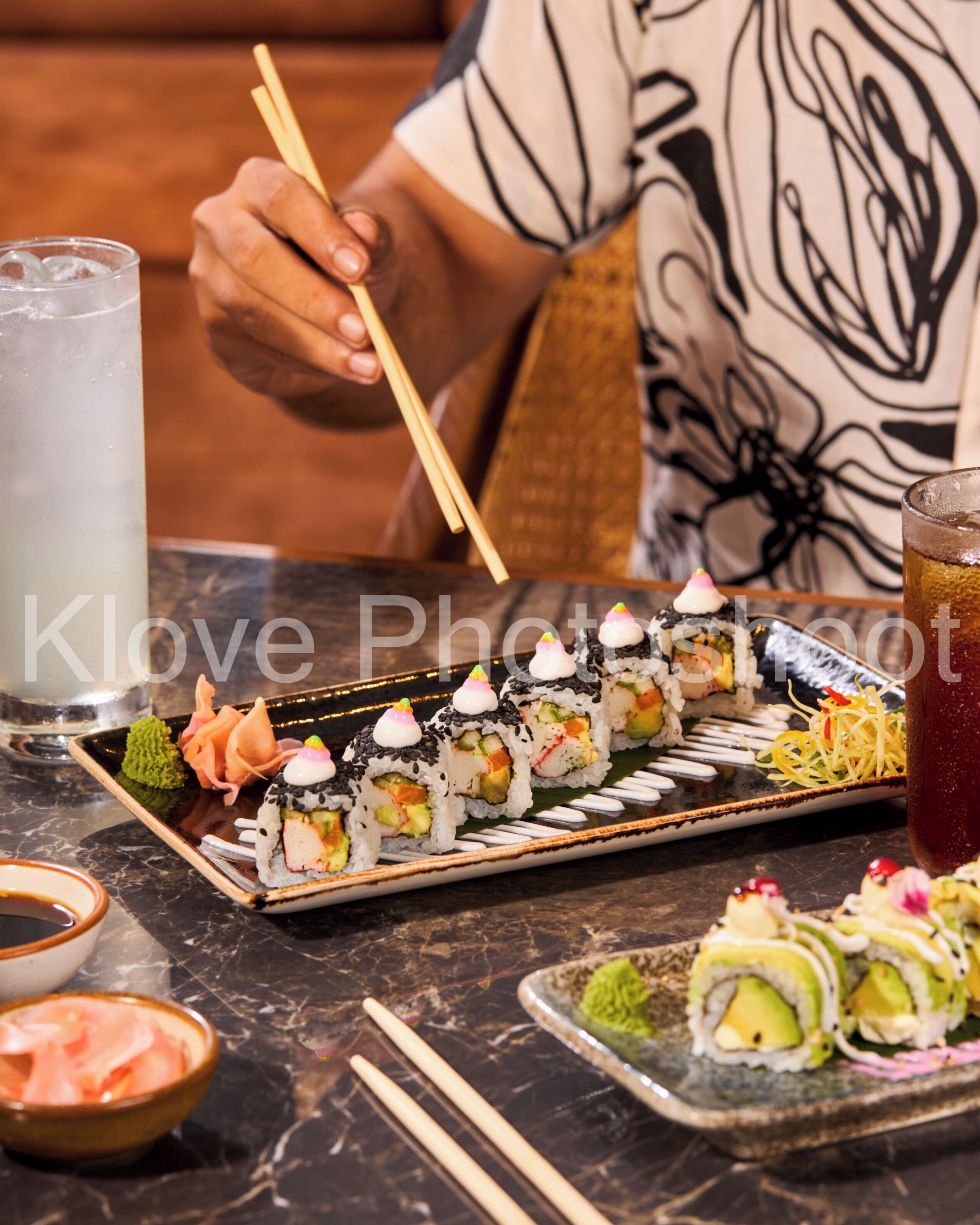 A variety of sushi on a tray, a glass of iced tea, and a bowl of soup.
