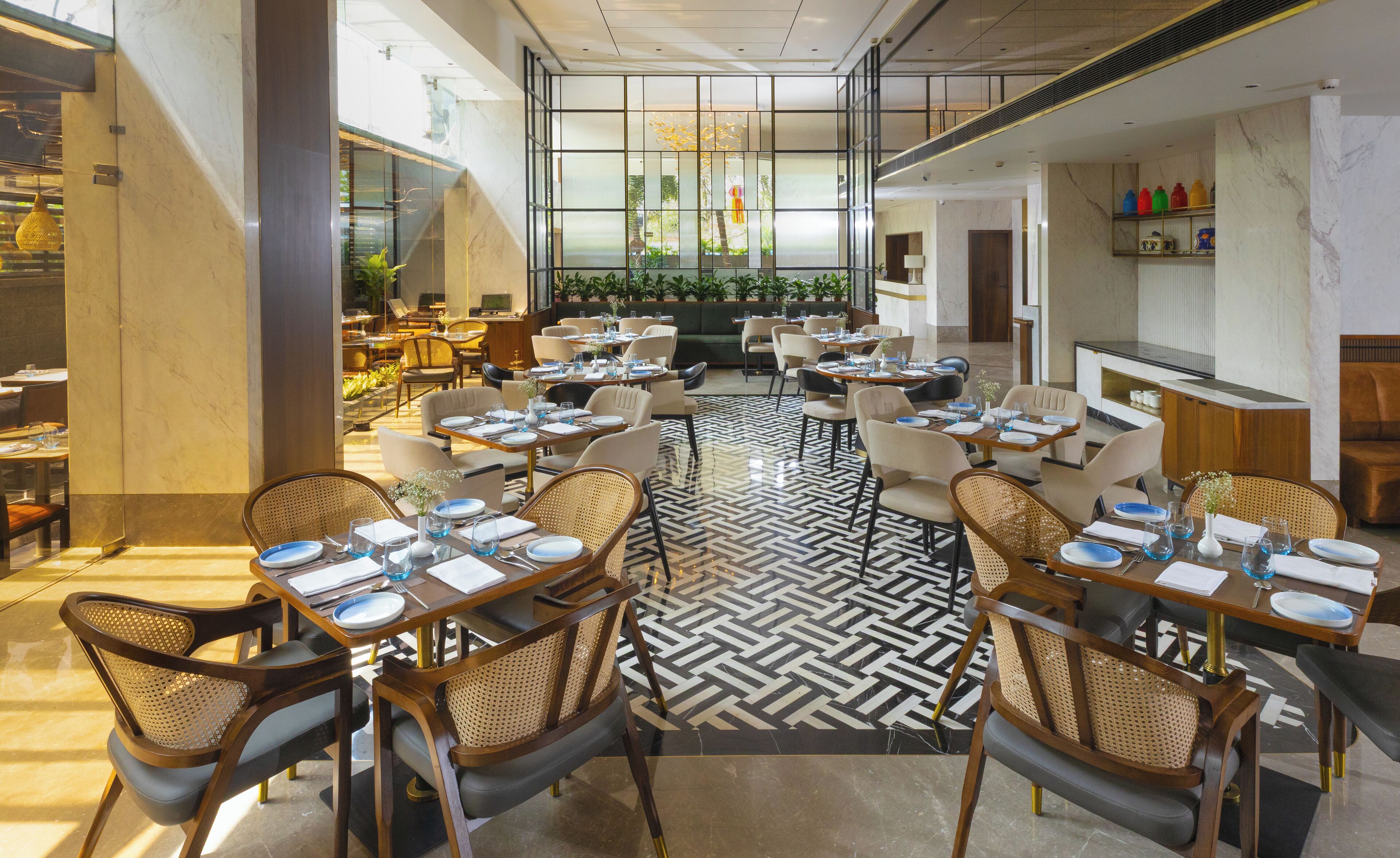Un restaurant spacieux avec de hauts plafonds, un mobilier moderne et un espace de repos central doté d’un sol à motifs.