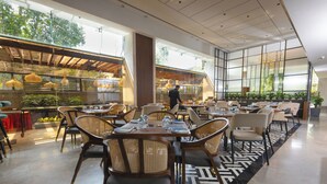 Un ristorante moderno con soffitti alti, ampie finestre e un mix di mobili in legno e vimini.