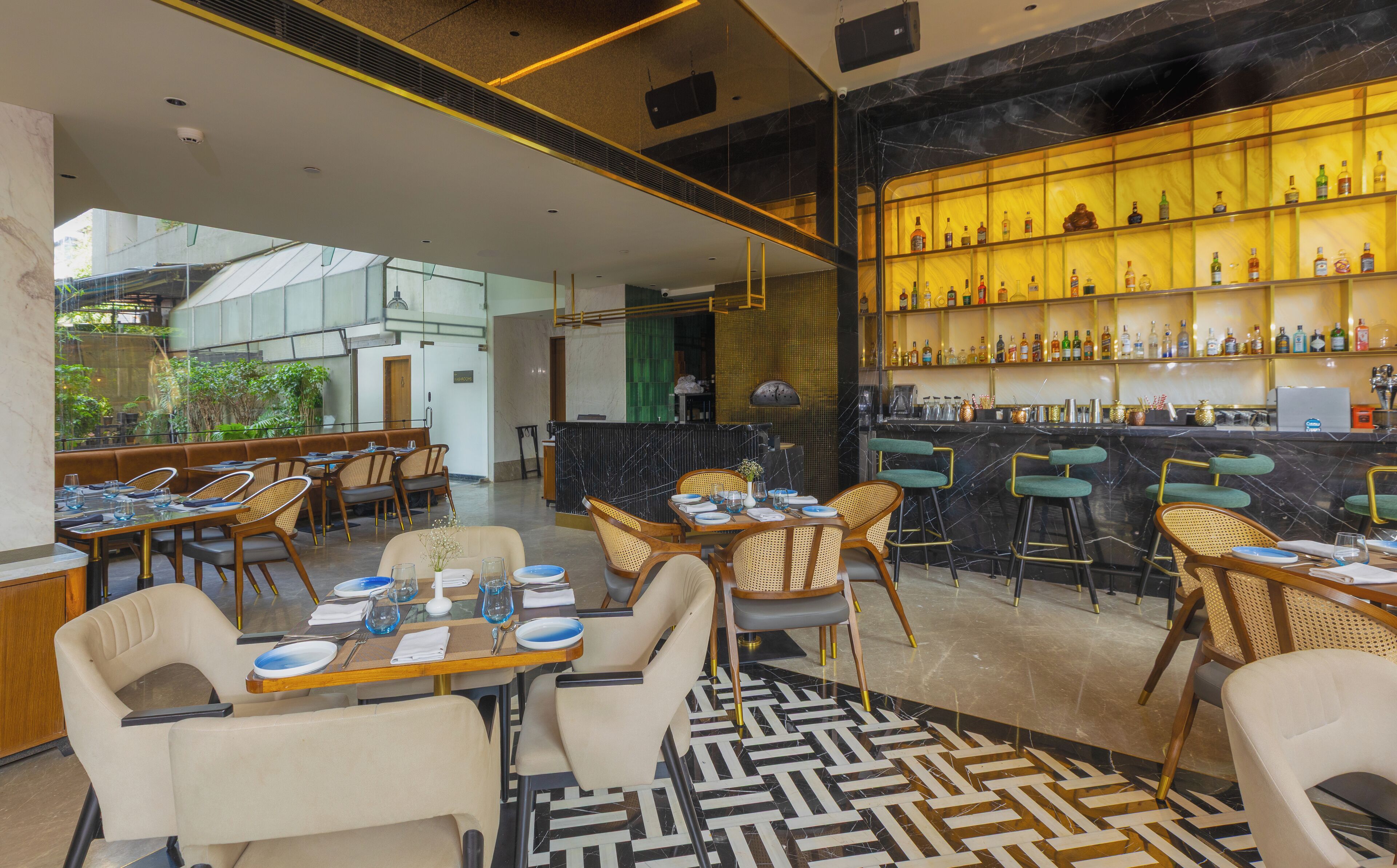 A modern restaurant with a bar area, featuring a mix of seating options including tables and bar stools, and a patterned floor.