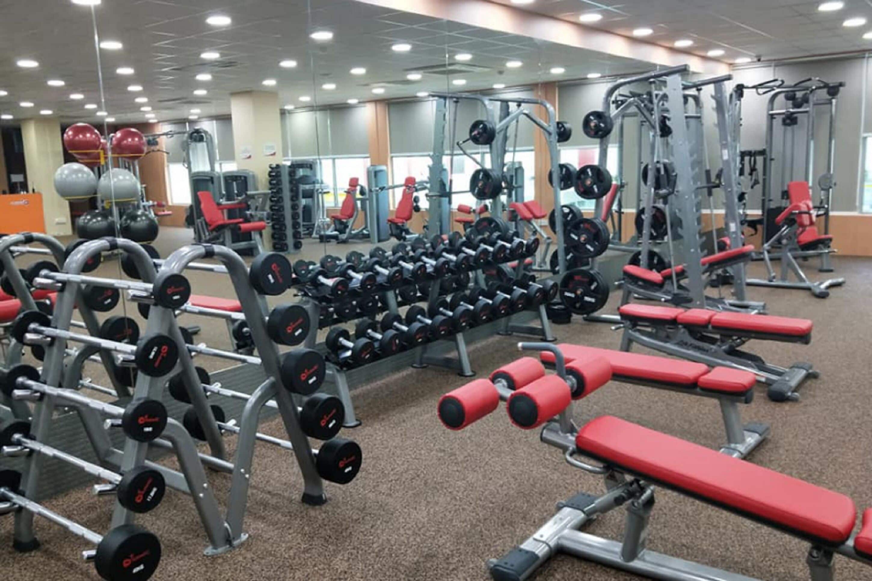 A gym with various weightlifting equipment, including dumbbells and benches.