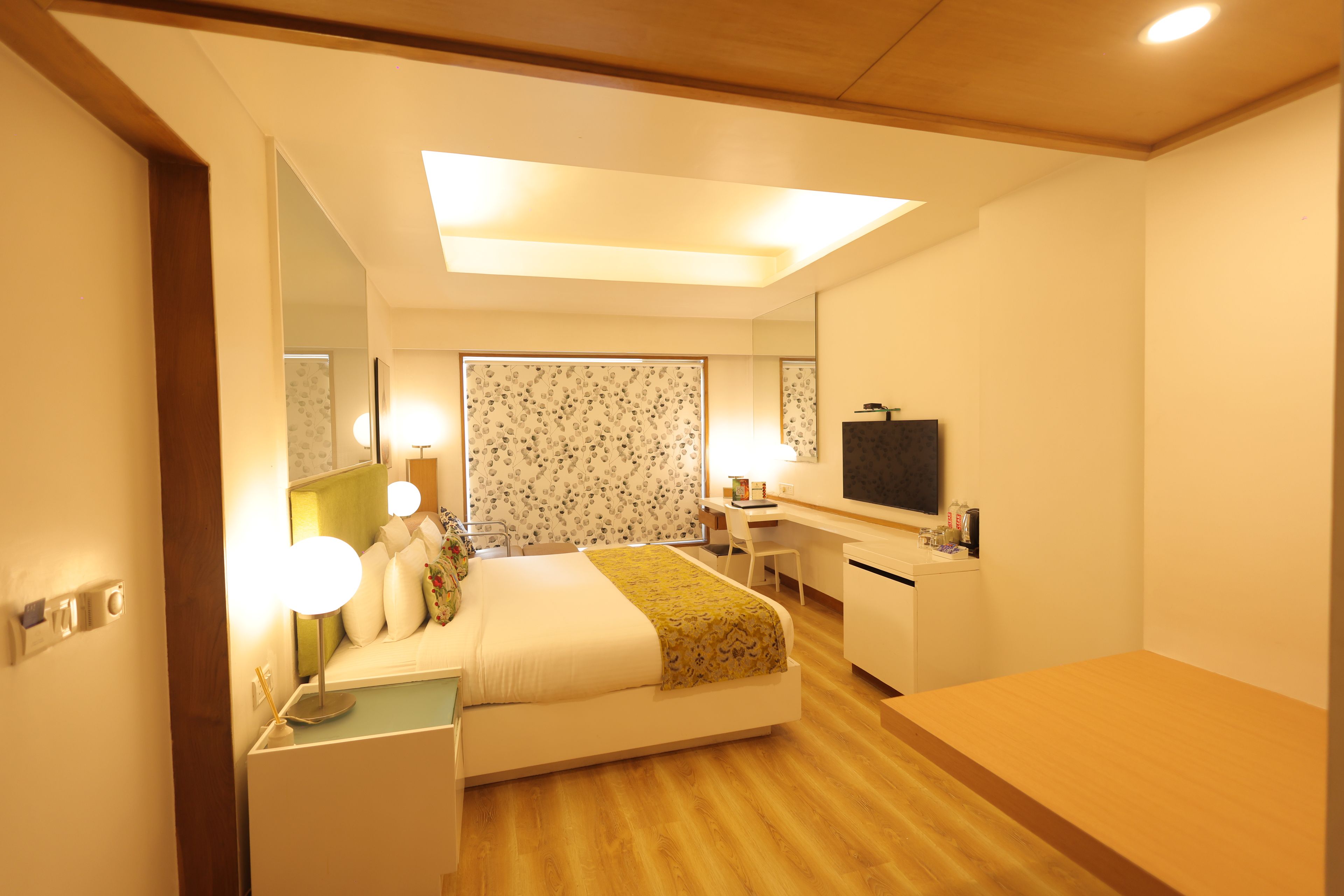 Una camera d'albergo con un letto, comodino, scrivania, sedia e televisore.