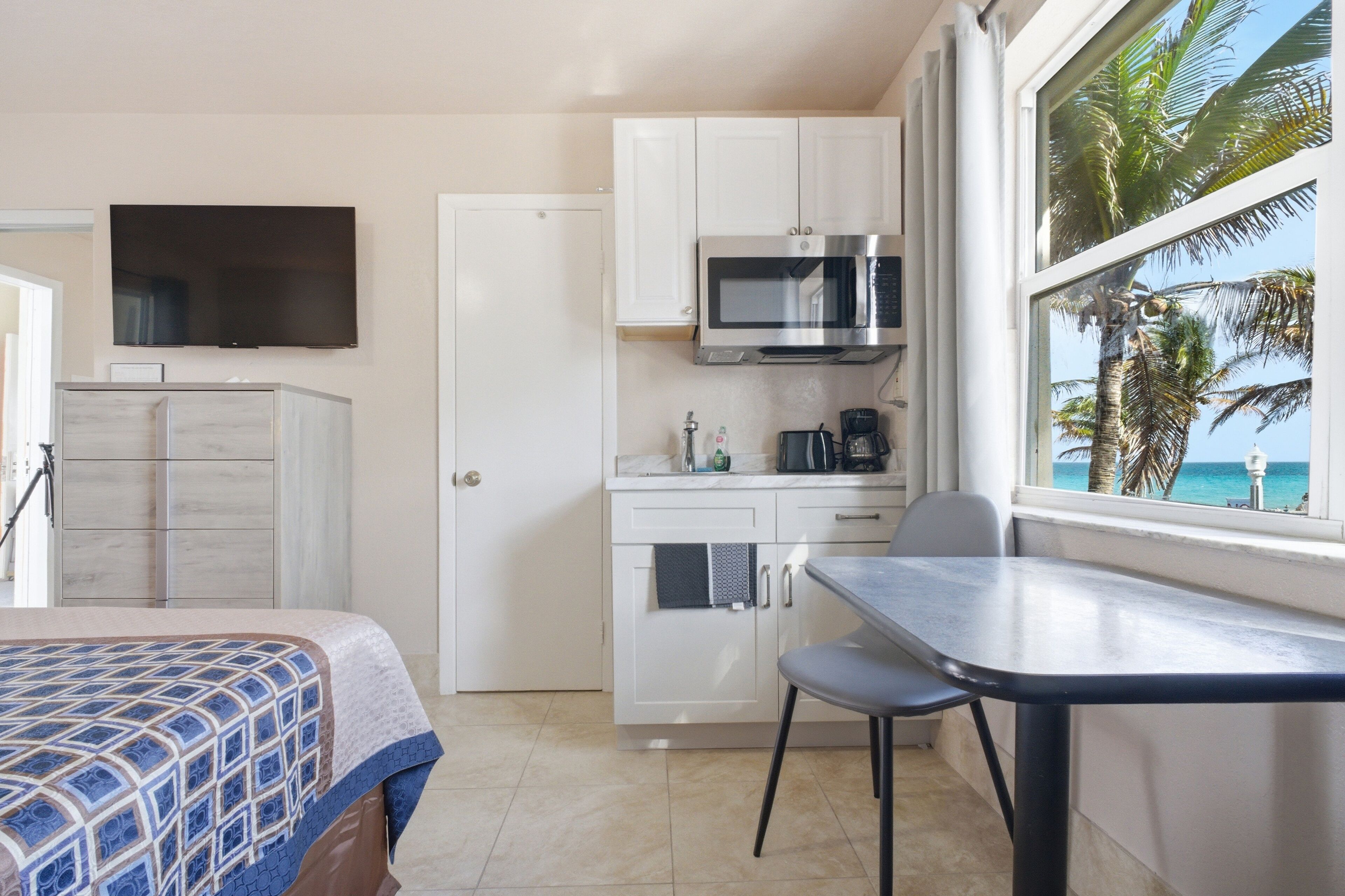A compact kitchen with a microwave, coffee maker, and a view of the ocean.