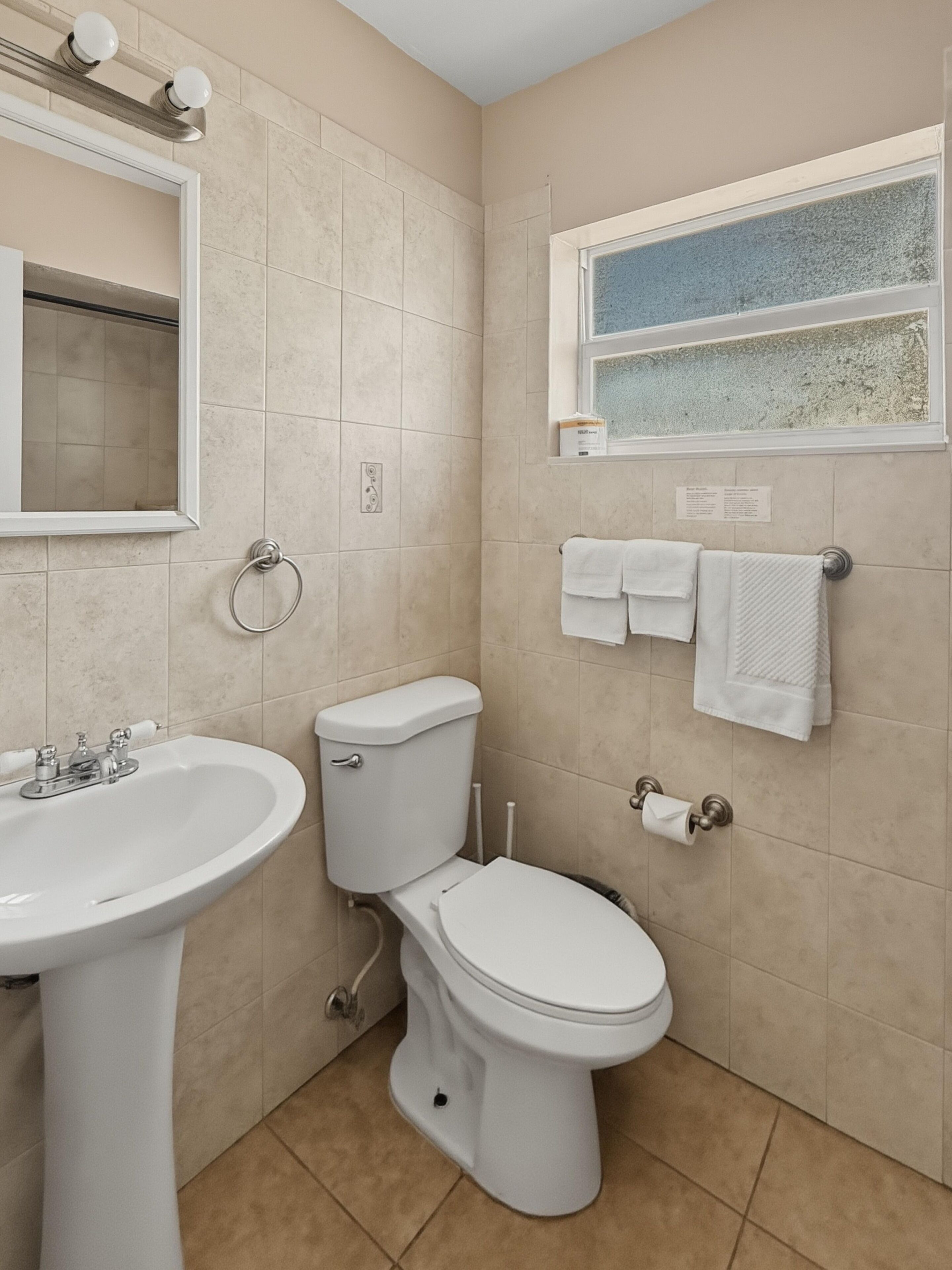 A bathroom with a sink, toilet, and a window with a view.