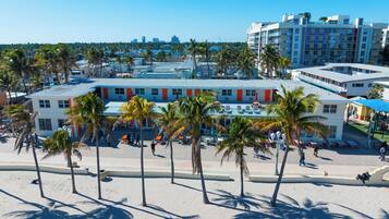 A beachfront hotel with multiple floors, palm trees, and a marina in the background.