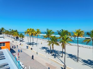 A beach with palm trees, a clear blue sky, and a calm sea. - La Terrace Oceanfront (Hollywood)