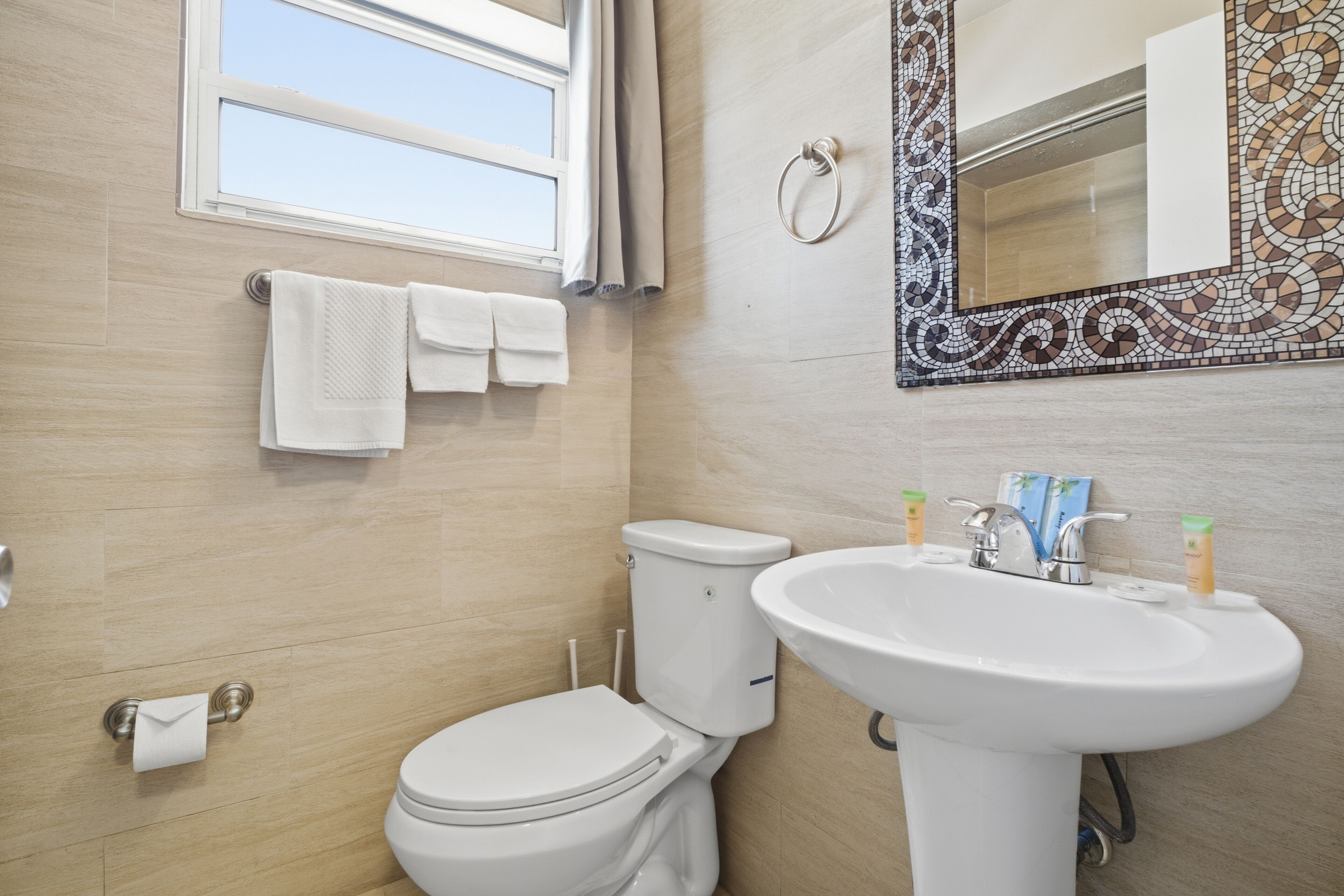 A bathroom with a toilet, sink, and a mirror with a mosaic frame.