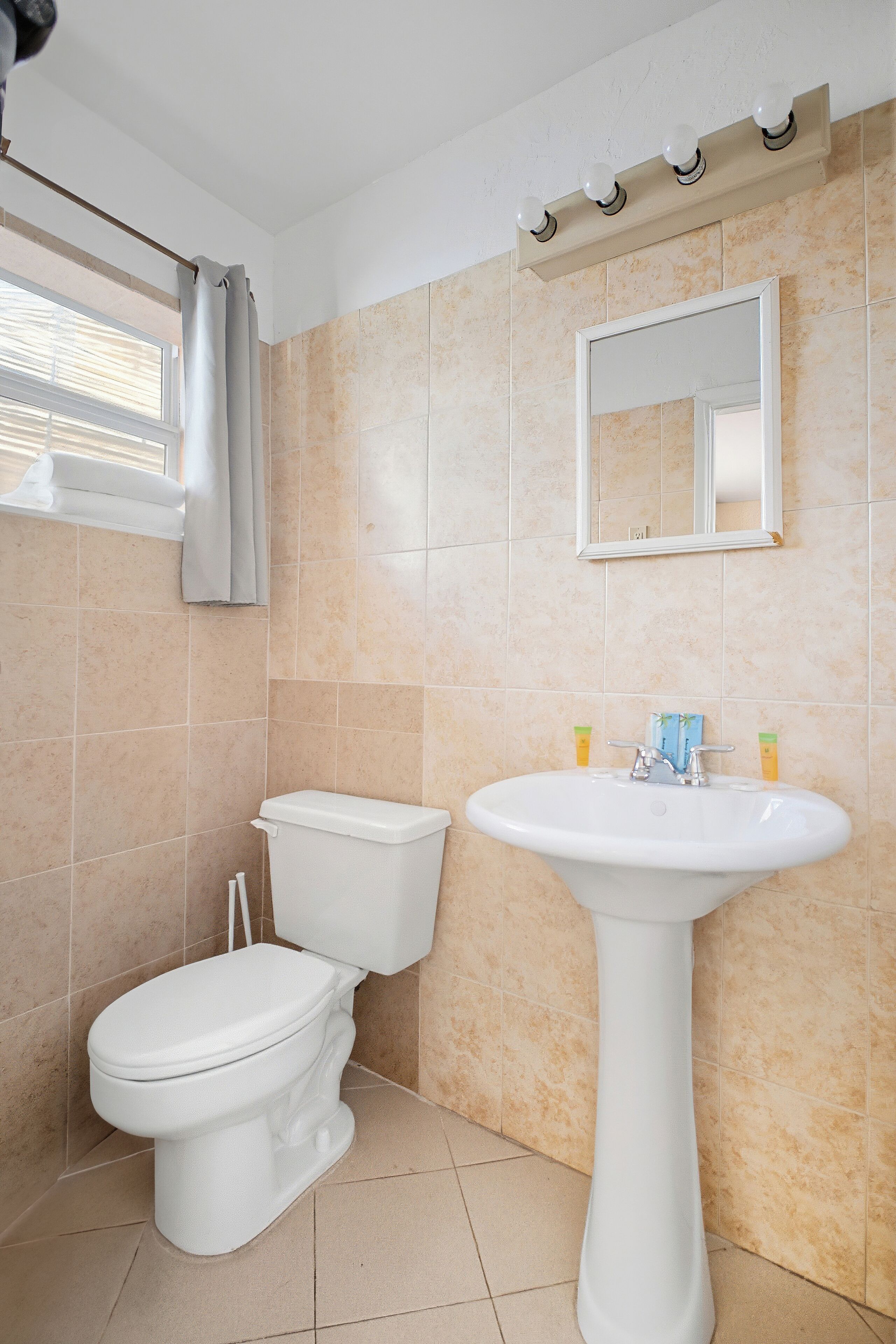 Un baño con inodoro, lavamanos y espejo.