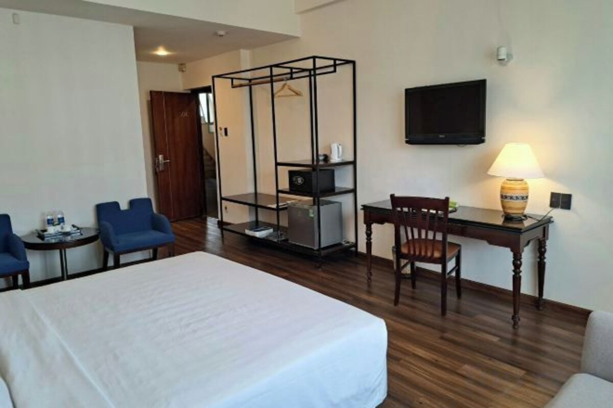 Een hotelkamer met een bed, bureau, stoel, televisie en lamp.