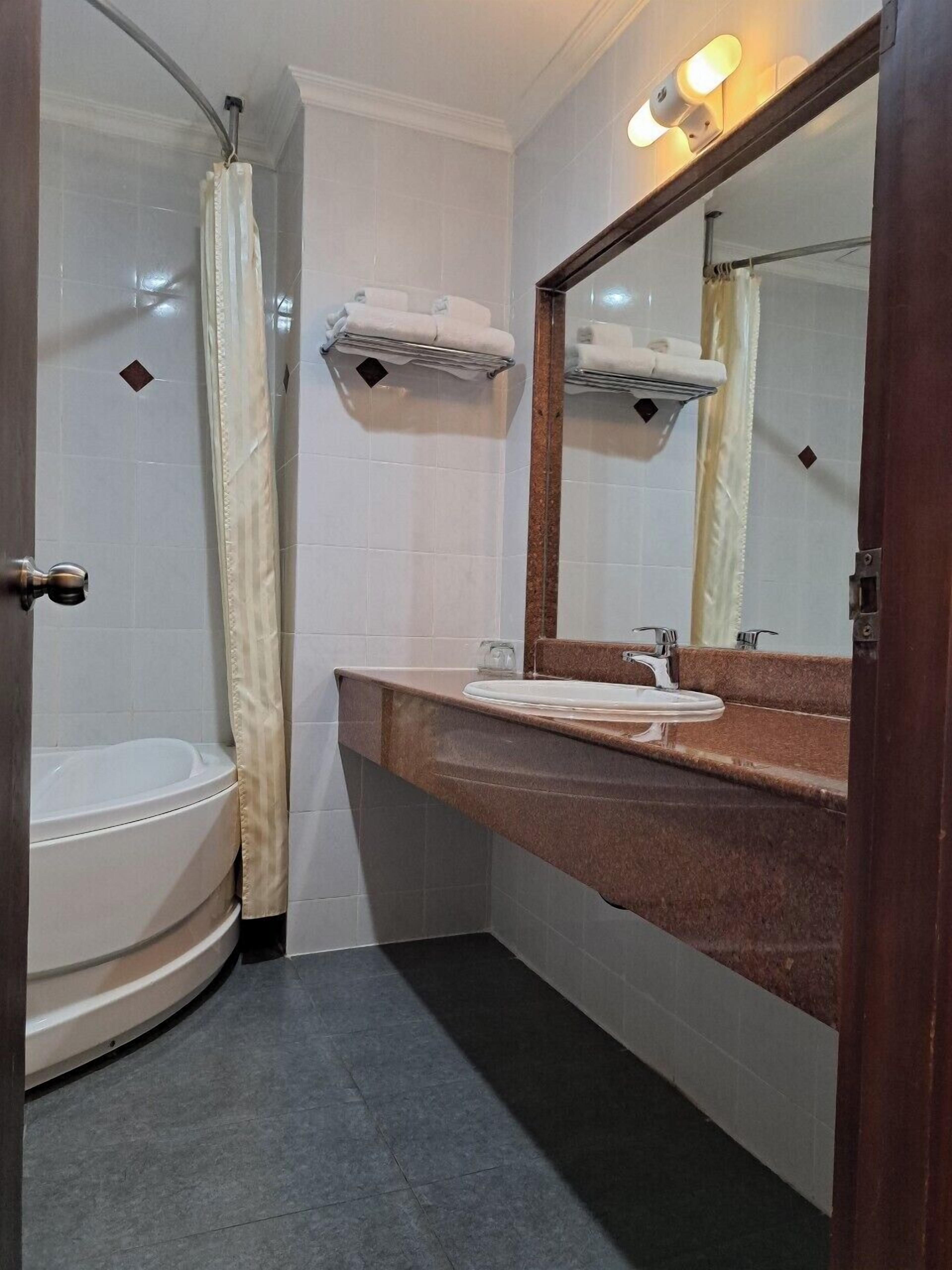 A bathroom with a bathtub, a sink, a mirror, and towel hooks.