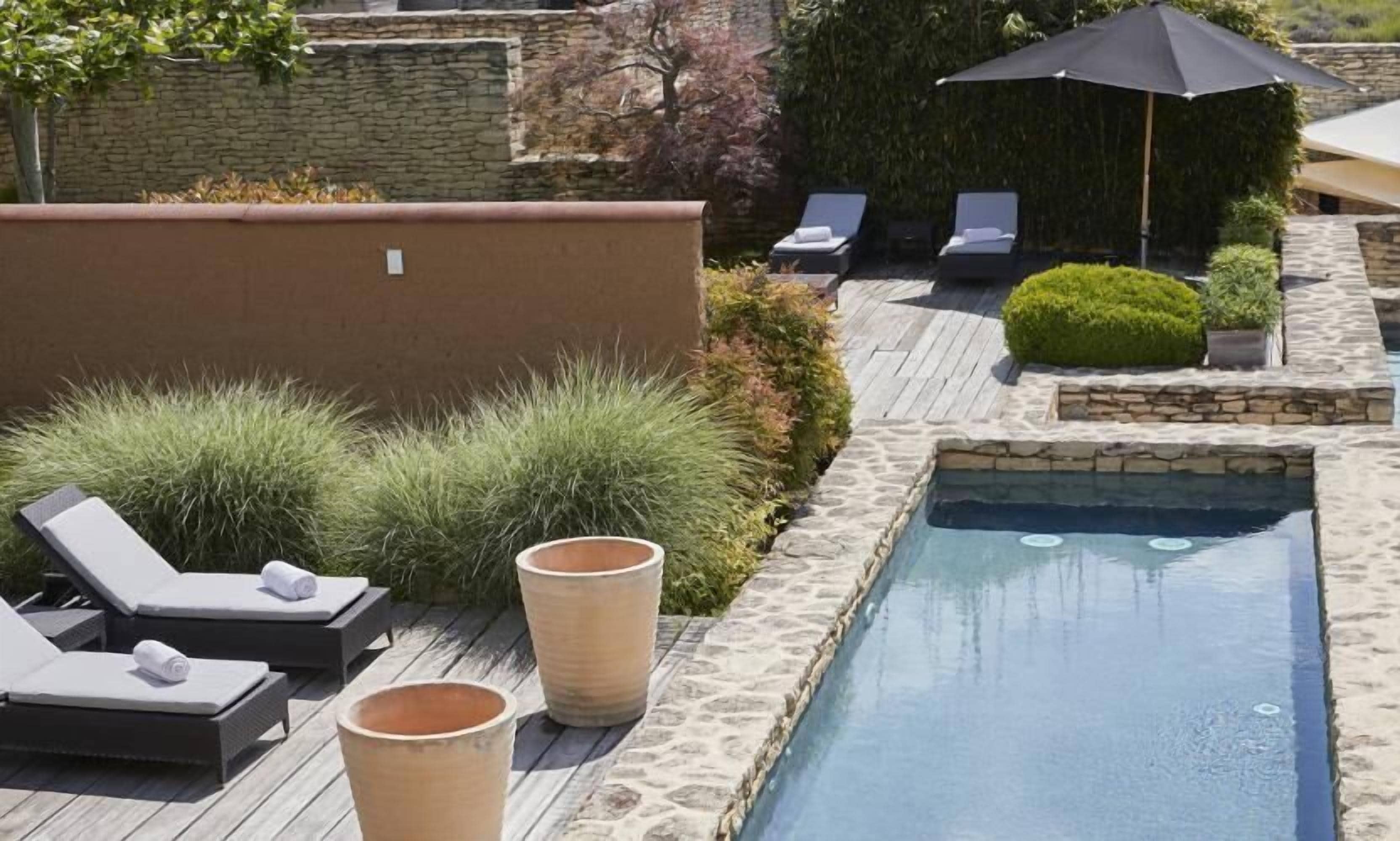Un espace piscine avec des chaises longues et une petite piscine.