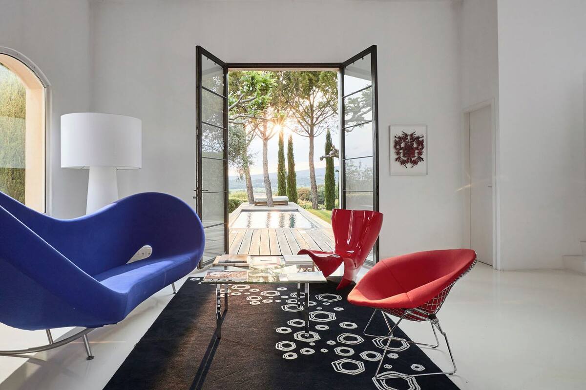 Een modern interieur met een blauwe stoel, een rode stoel en een witte vloerlamp.