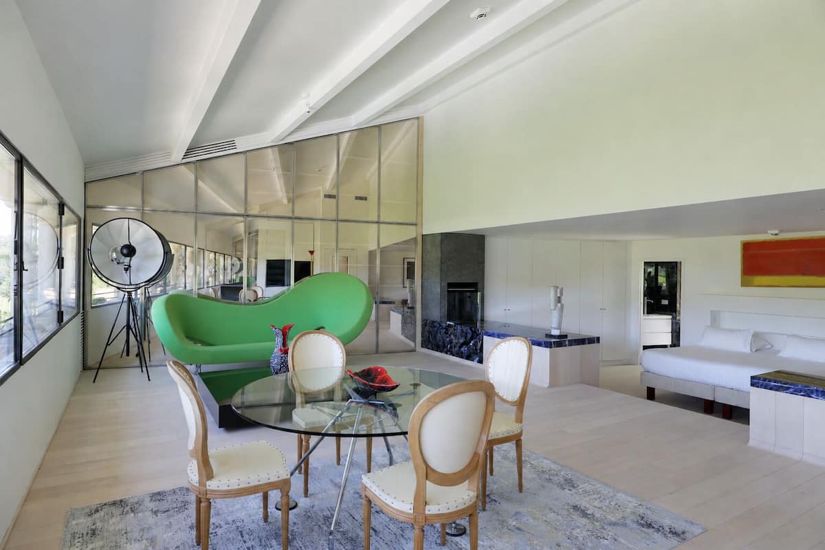 A modern living room with a green sofa, a glass coffee table, and a white couch.