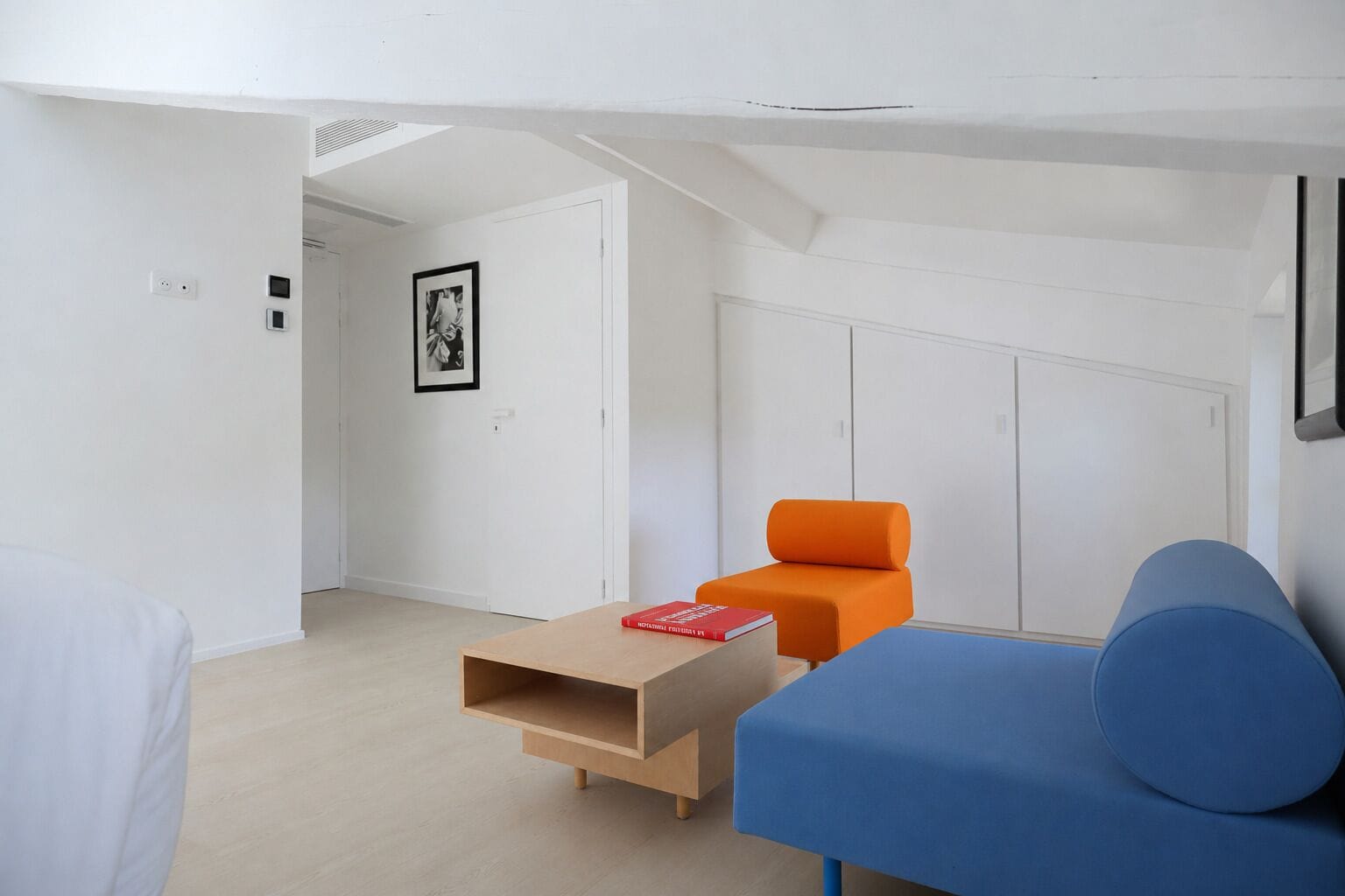 Une pièce moderne et minimaliste, avec un canapé bleu, un fauteuil orange et une table basse en bois.