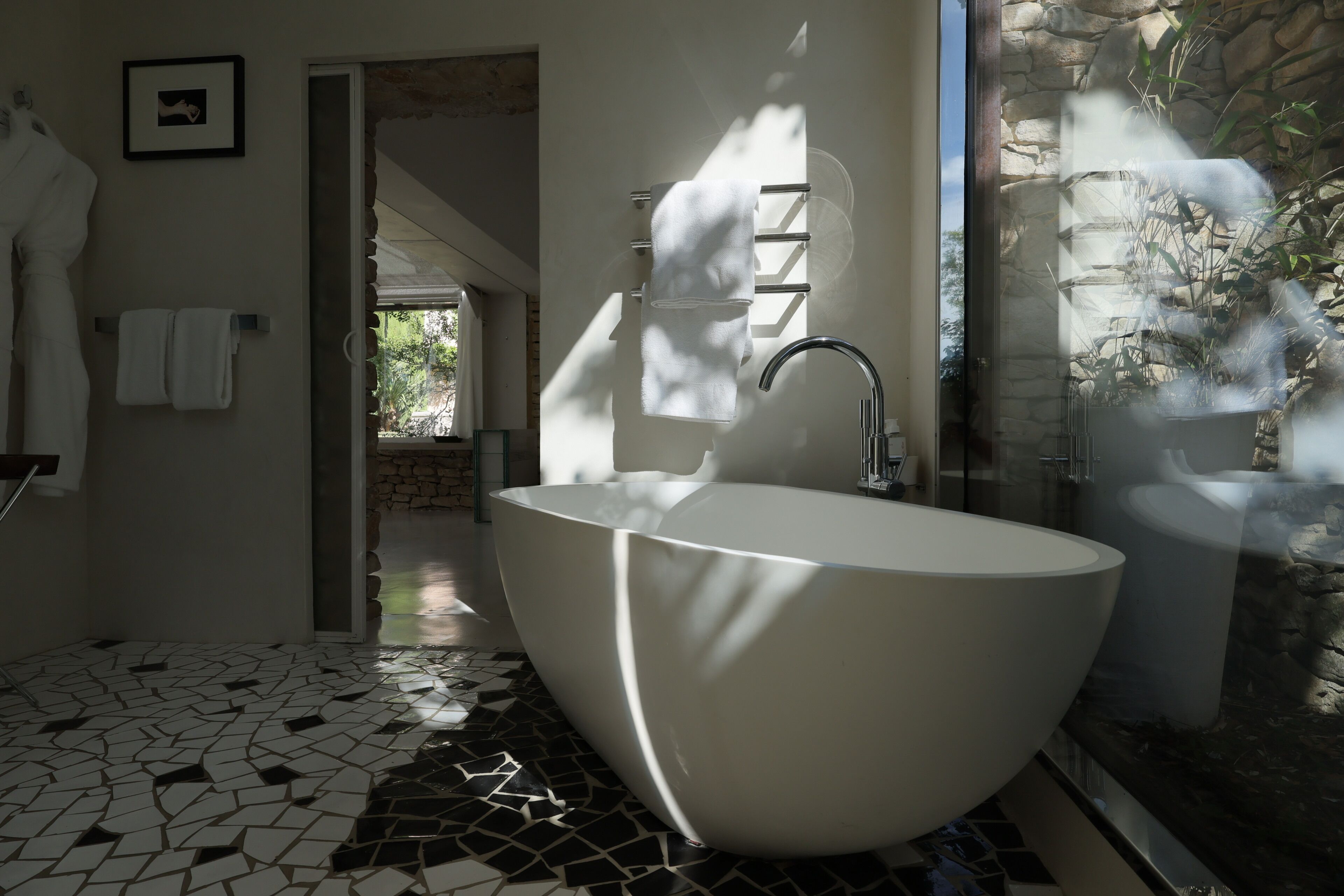 Een moderne badkamer met een vrijstaand bad, een douchecabine met glazen wanden en een mozaïekvloer.