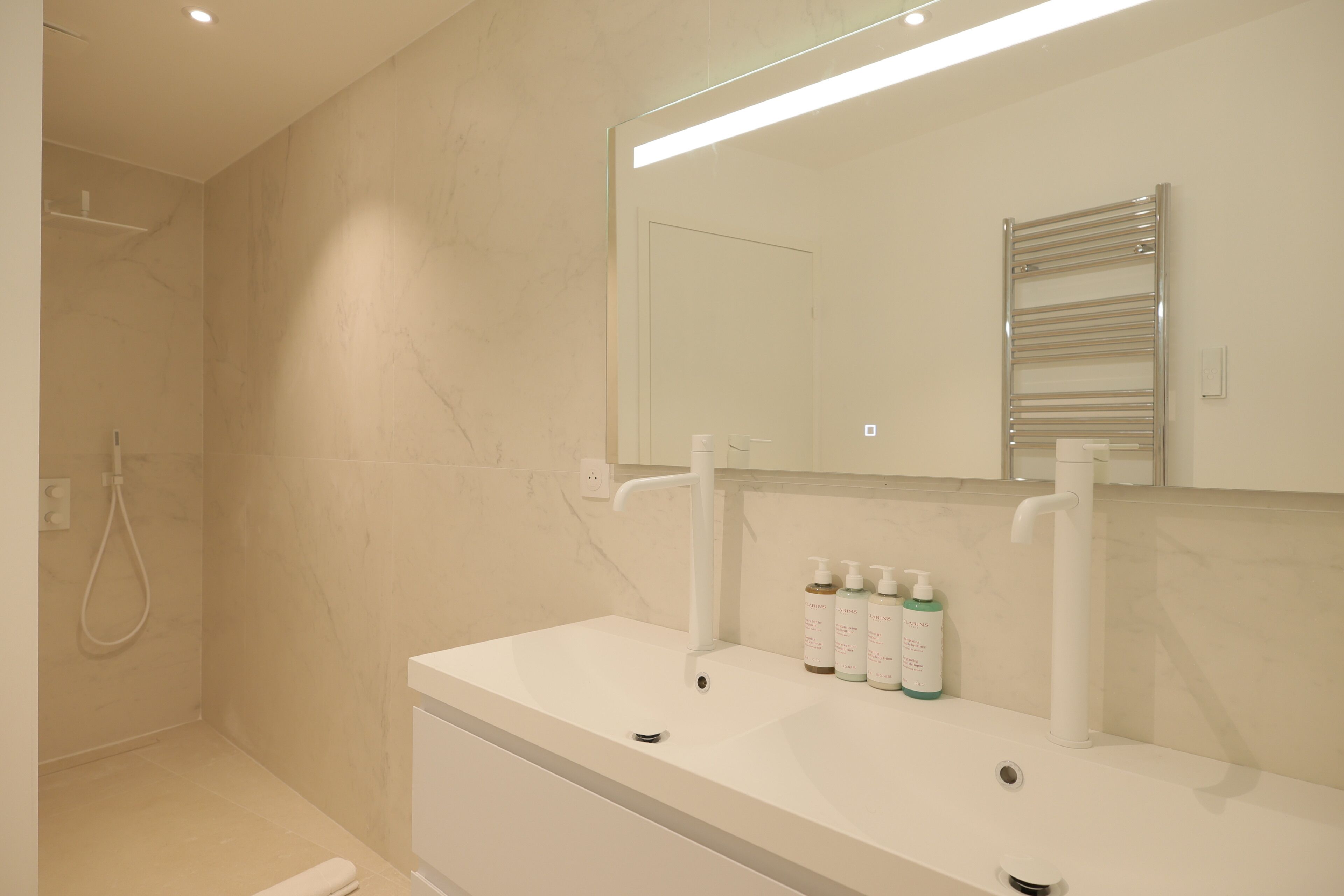 Un baño moderno con lavabo, espejo y ducha blancos.